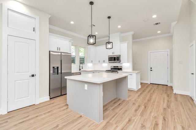 kitchen with decorative light fixtures, a kitchen island, white cabinetry, and appliances with stainless steel finishes