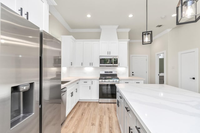 kitchen with decorative backsplash, appliances with stainless steel finishes, white cabinetry, and pendant lighting