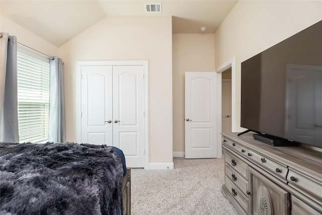 carpeted bedroom with a closet and lofted ceiling