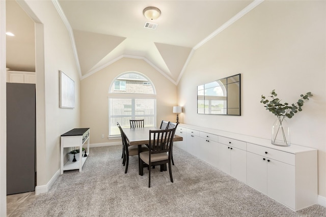 dining area featuring crown molding, lofted ceiling, and light carpet