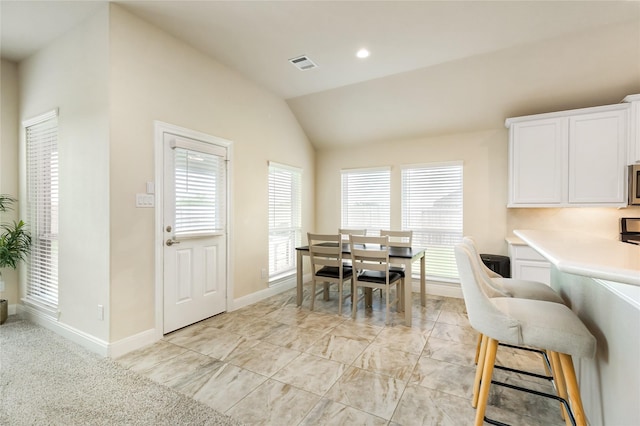 carpeted dining area featuring vaulted ceiling and a healthy amount of sunlight