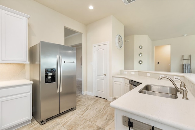 kitchen with decorative backsplash, white cabinetry, sink, and appliances with stainless steel finishes