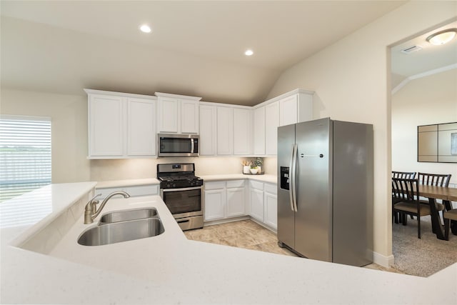 kitchen with white cabinets, sink, lofted ceiling, and stainless steel appliances