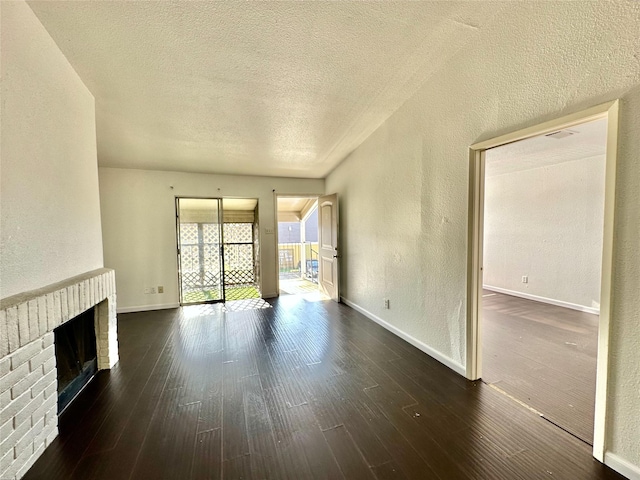 unfurnished living room featuring a textured ceiling, dark hardwood / wood-style floors, and a brick fireplace