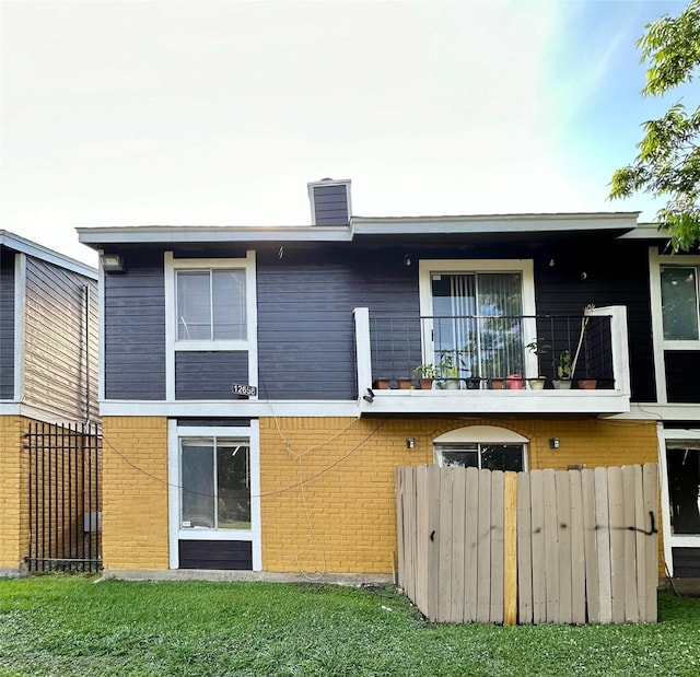 back of property featuring a balcony and a yard