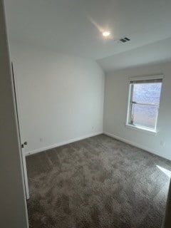 unfurnished room with dark carpet and lofted ceiling