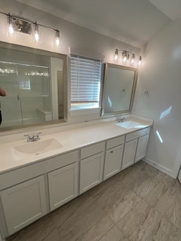 bathroom featuring vanity, a shower with shower door, and vaulted ceiling