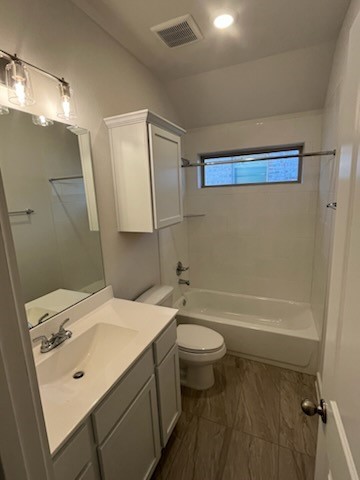 full bathroom with toilet, vanity, bathing tub / shower combination, and lofted ceiling