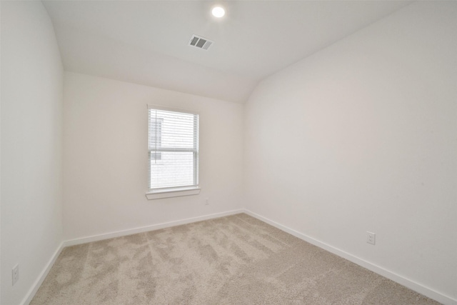 spare room with vaulted ceiling and light colored carpet