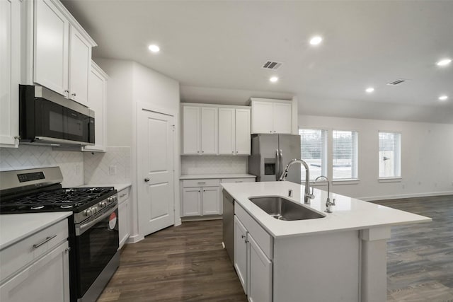 kitchen with sink, appliances with stainless steel finishes, white cabinetry, an island with sink, and dark hardwood / wood-style flooring