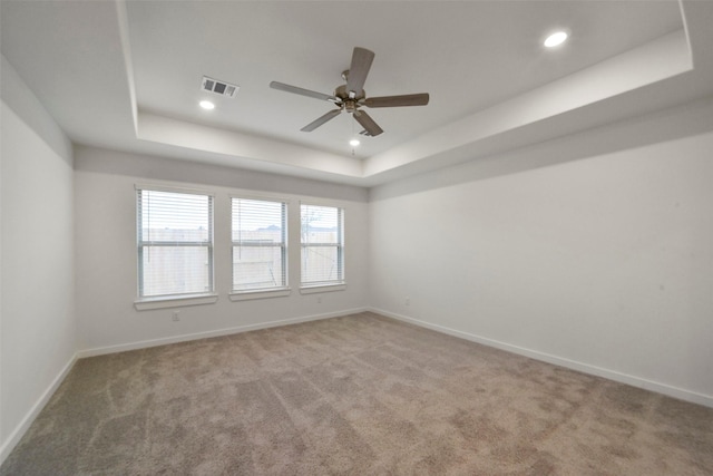 carpeted spare room with ceiling fan and a tray ceiling