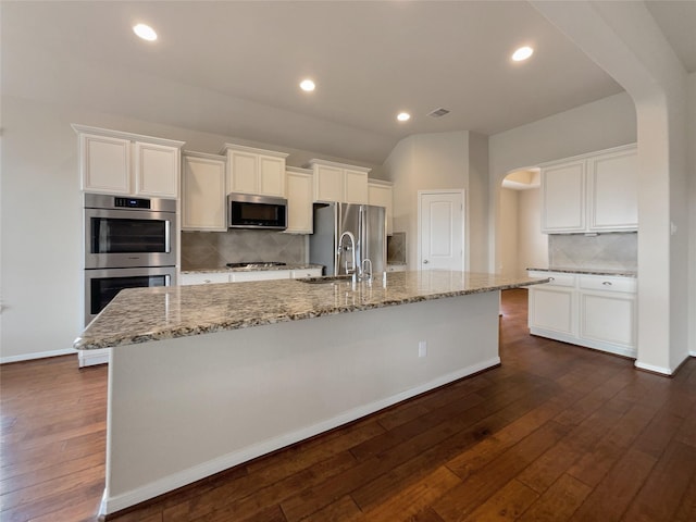 kitchen with white cabinetry, sink, stainless steel appliances, backsplash, and a spacious island