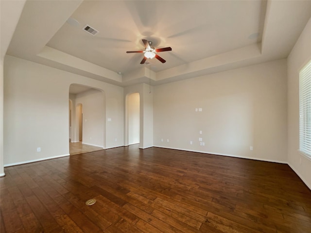 empty room featuring ceiling fan, dark hardwood / wood-style flooring, and a raised ceiling