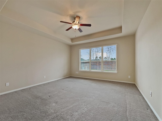 spare room featuring carpet flooring, ceiling fan, and a raised ceiling