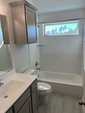 full bathroom featuring tiled shower / bath combo, toilet, and vanity