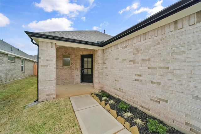 entrance to property featuring a patio and a yard