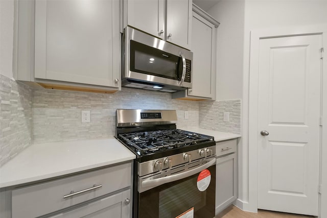 kitchen featuring gray cabinetry, decorative backsplash, and stainless steel appliances