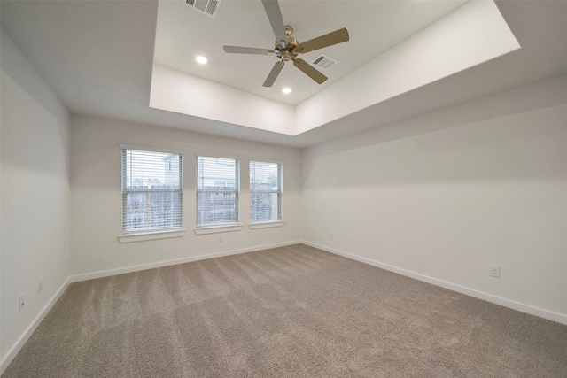 carpeted spare room featuring ceiling fan and a tray ceiling