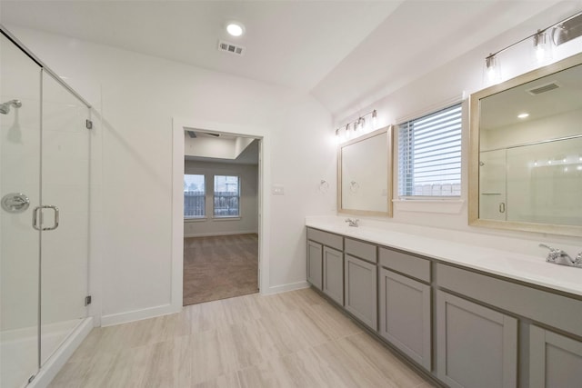 bathroom with vanity, a shower with shower door, and lofted ceiling