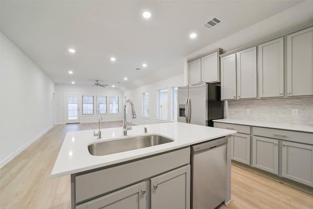 kitchen featuring appliances with stainless steel finishes, sink, gray cabinetry, and a kitchen island with sink