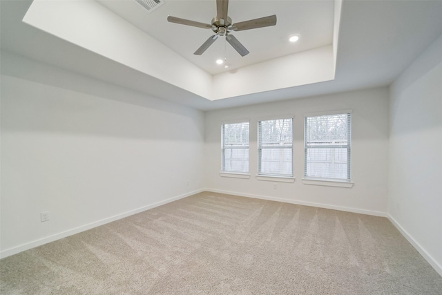 unfurnished room with a raised ceiling, carpet floors, and ceiling fan