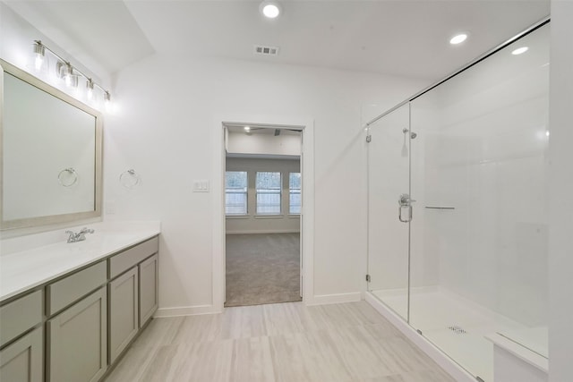 bathroom featuring a shower with door and vanity