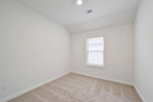 spare room featuring vaulted ceiling and light carpet