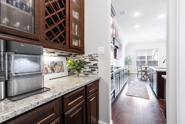 kitchen with dark brown cabinetry, crown molding, dark hardwood / wood-style flooring, and light stone countertops