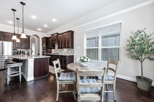 dining room with sink, dark hardwood / wood-style floors, and ornamental molding