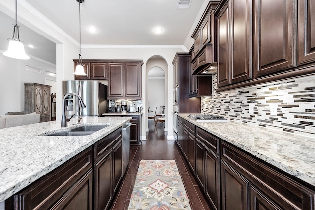 kitchen with sink, stainless steel appliances, dark wood-type flooring, hanging light fixtures, and dark brown cabinets