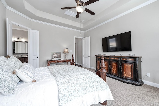 carpeted bedroom with ceiling fan, crown molding, ensuite bathroom, and a tray ceiling