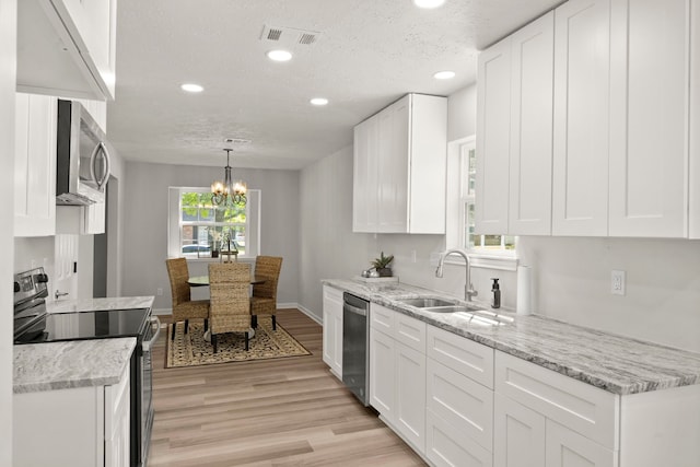 kitchen featuring a chandelier, white cabinetry, stainless steel appliances, and a textured ceiling