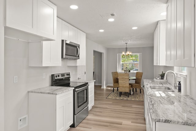 kitchen featuring an inviting chandelier, sink, hanging light fixtures, white cabinetry, and stainless steel appliances