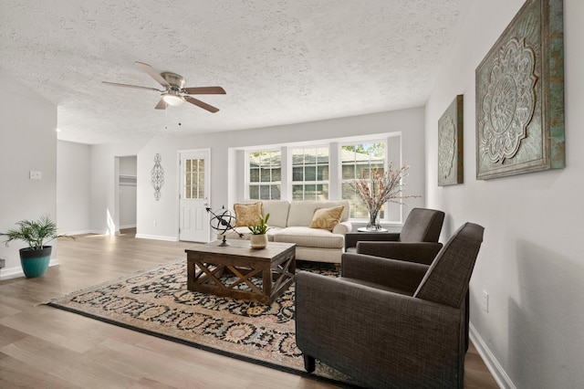 living room featuring ceiling fan, wood-type flooring, and a textured ceiling