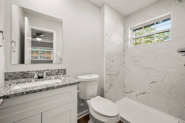 bathroom with a tile shower, vanity, ceiling fan, and a healthy amount of sunlight