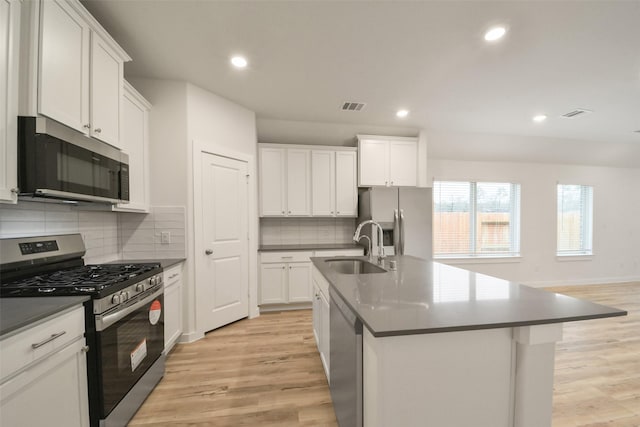 kitchen featuring white cabinetry, appliances with stainless steel finishes, sink, and a center island with sink