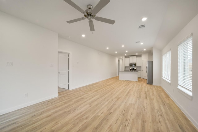 unfurnished living room featuring ceiling fan and light hardwood / wood-style floors