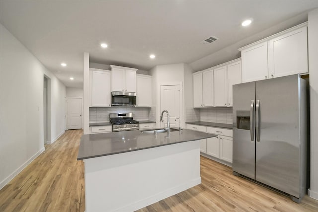 kitchen featuring sink, appliances with stainless steel finishes, white cabinetry, a kitchen island with sink, and light hardwood / wood-style floors