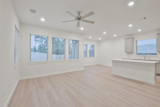 unfurnished living room with ceiling fan, sink, and light hardwood / wood-style floors