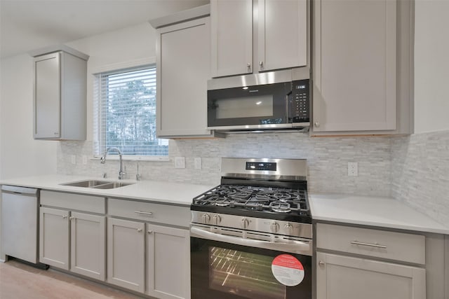 kitchen featuring stainless steel appliances, tasteful backsplash, gray cabinetry, and sink