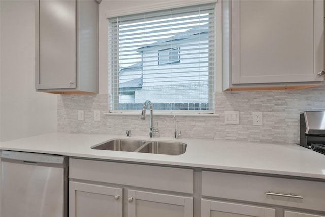 kitchen featuring stainless steel dishwasher, decorative backsplash, gray cabinets, and sink