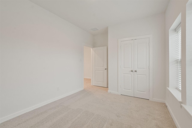 unfurnished bedroom with light carpet and a closet