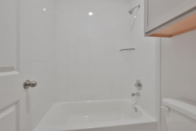 bathroom featuring toilet and tiled shower / bath