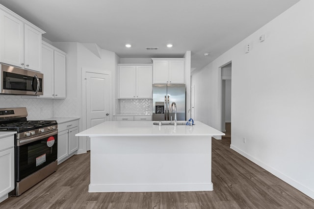 kitchen featuring a center island with sink, white cabinets, sink, decorative backsplash, and appliances with stainless steel finishes