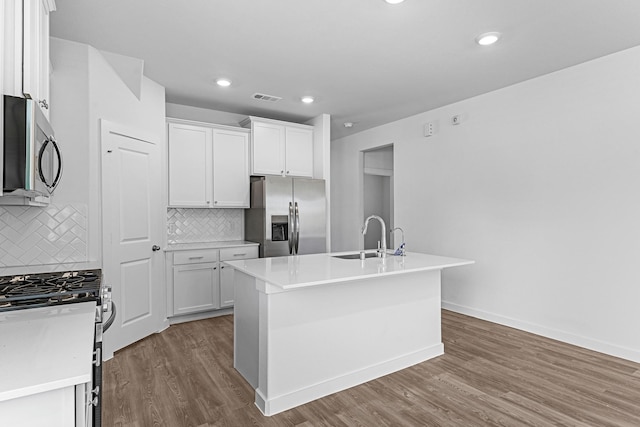 kitchen with white cabinetry, decorative backsplash, a kitchen island with sink, and appliances with stainless steel finishes