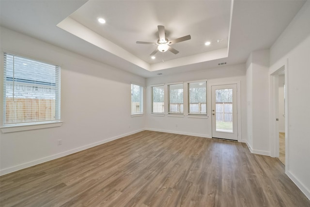 spare room featuring hardwood / wood-style flooring, ceiling fan, and a tray ceiling