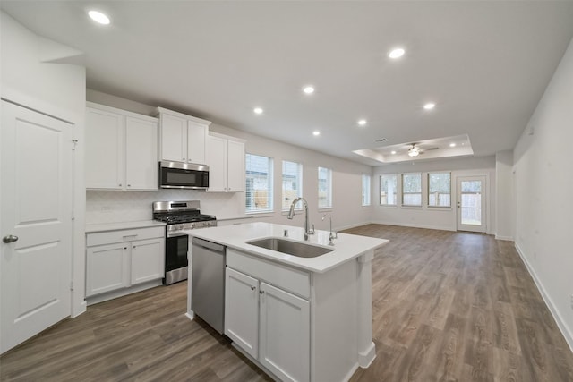 kitchen featuring an island with sink, sink, white cabinets, dark hardwood / wood-style flooring, and stainless steel appliances