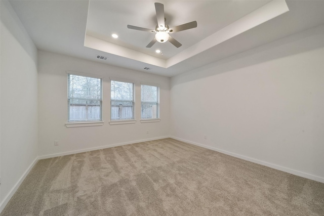 carpeted empty room featuring a tray ceiling and ceiling fan