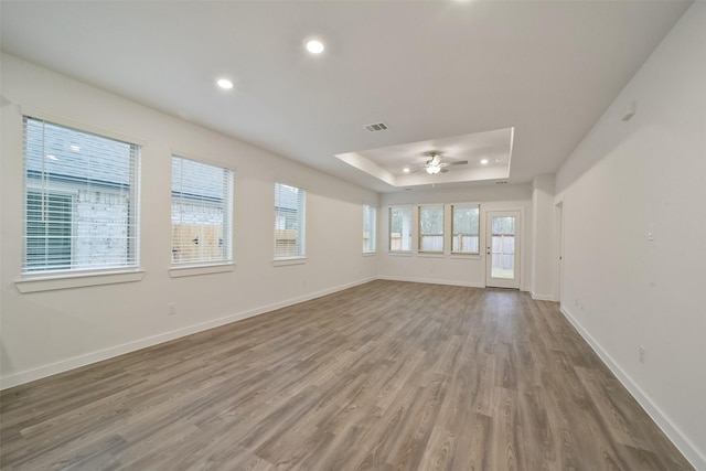 spare room with ceiling fan, a tray ceiling, and hardwood / wood-style floors