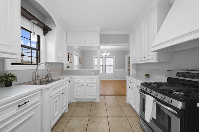 kitchen featuring hanging light fixtures, white cabinetry, gas range, light tile patterned flooring, and custom range hood